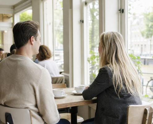 Twee ondernemers in een rustig gesprek aan een tafel bij het raam